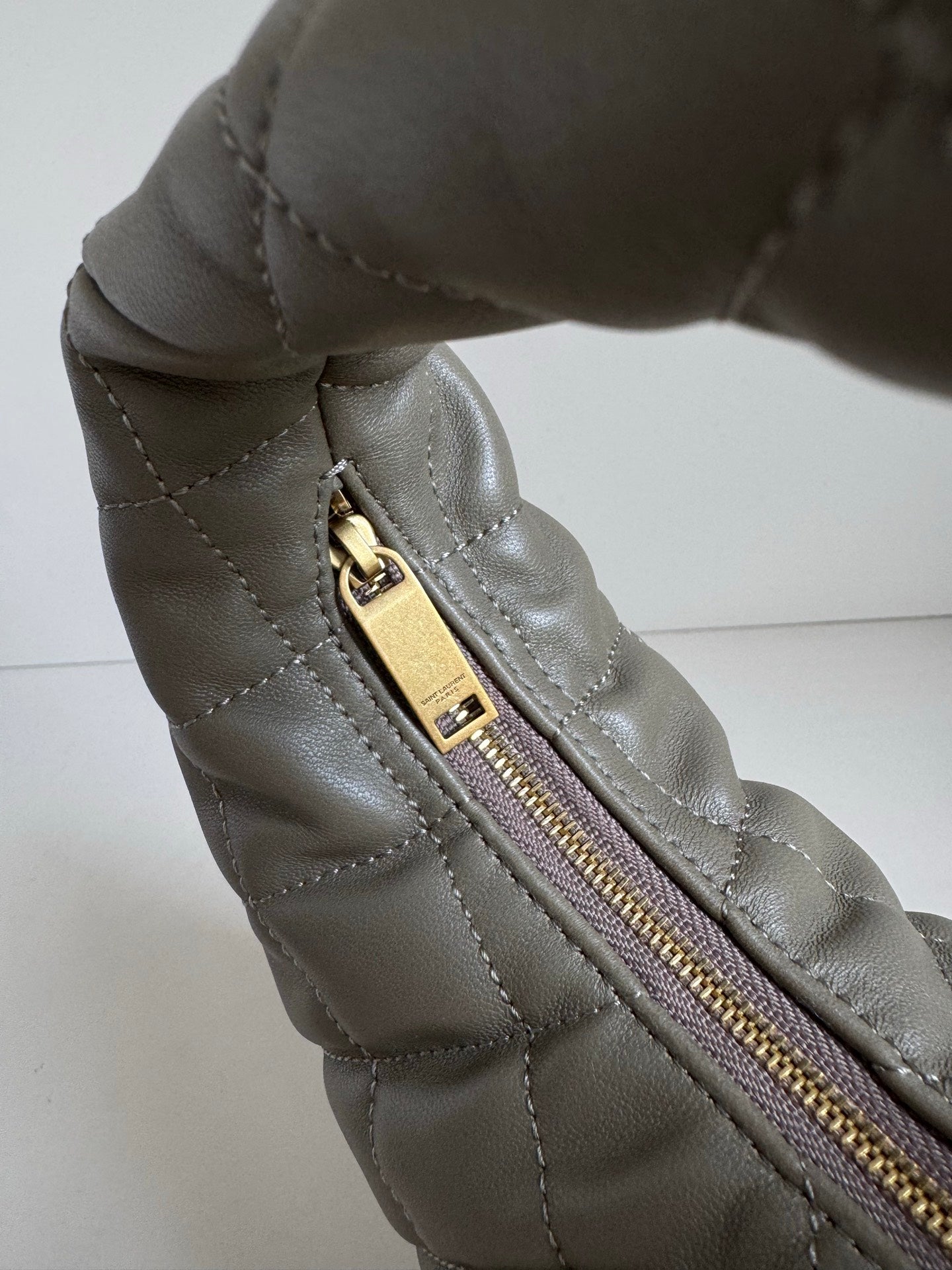Quilted hobo bag in metallic gray with gold zipper pull and stitched seam detail