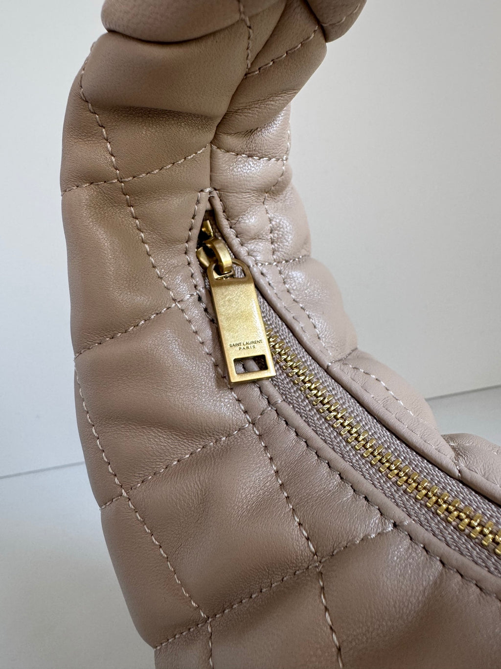 YSL quilted hobo bag close-up of gold zipper pull and top zip pocket