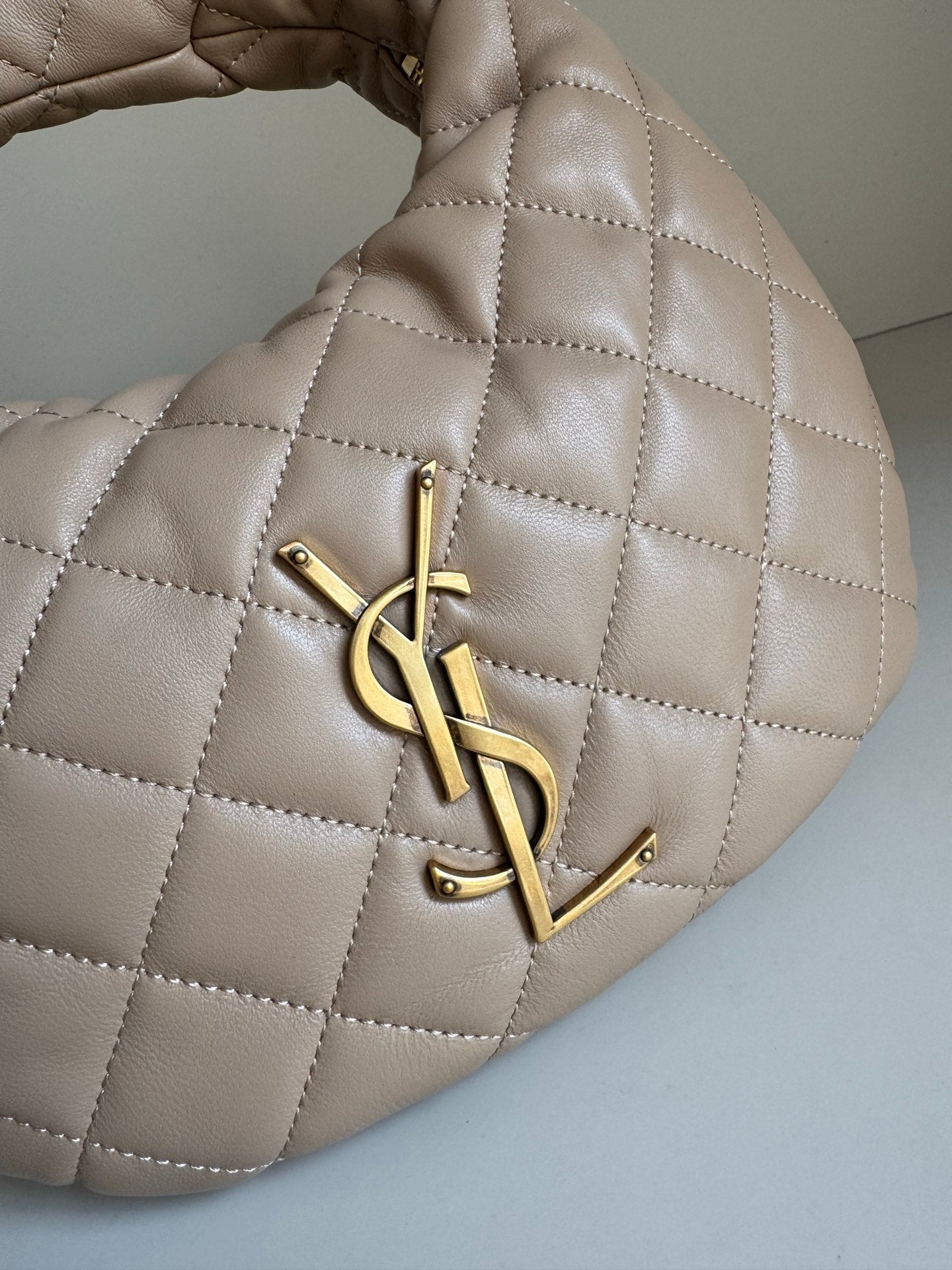 YSL quilted hobo bag detail with gold YSL logo hardware and diamond stitching