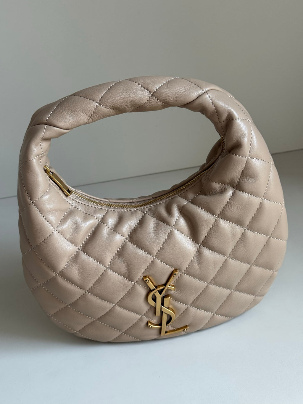 YSL quilted hobo bag front view with gold YSL logo and curved top opening