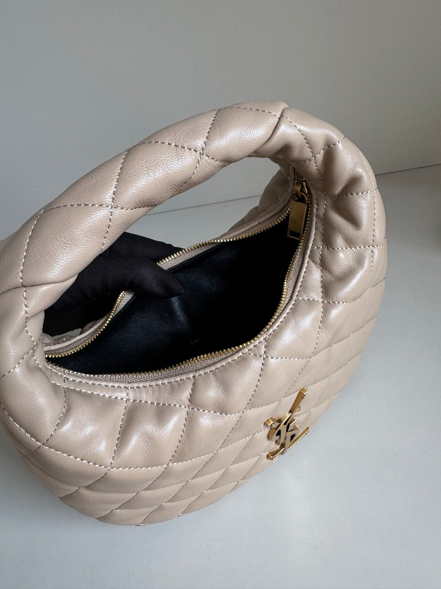 YSL quilted hobo bag open top showing black interior and gold zipper pull