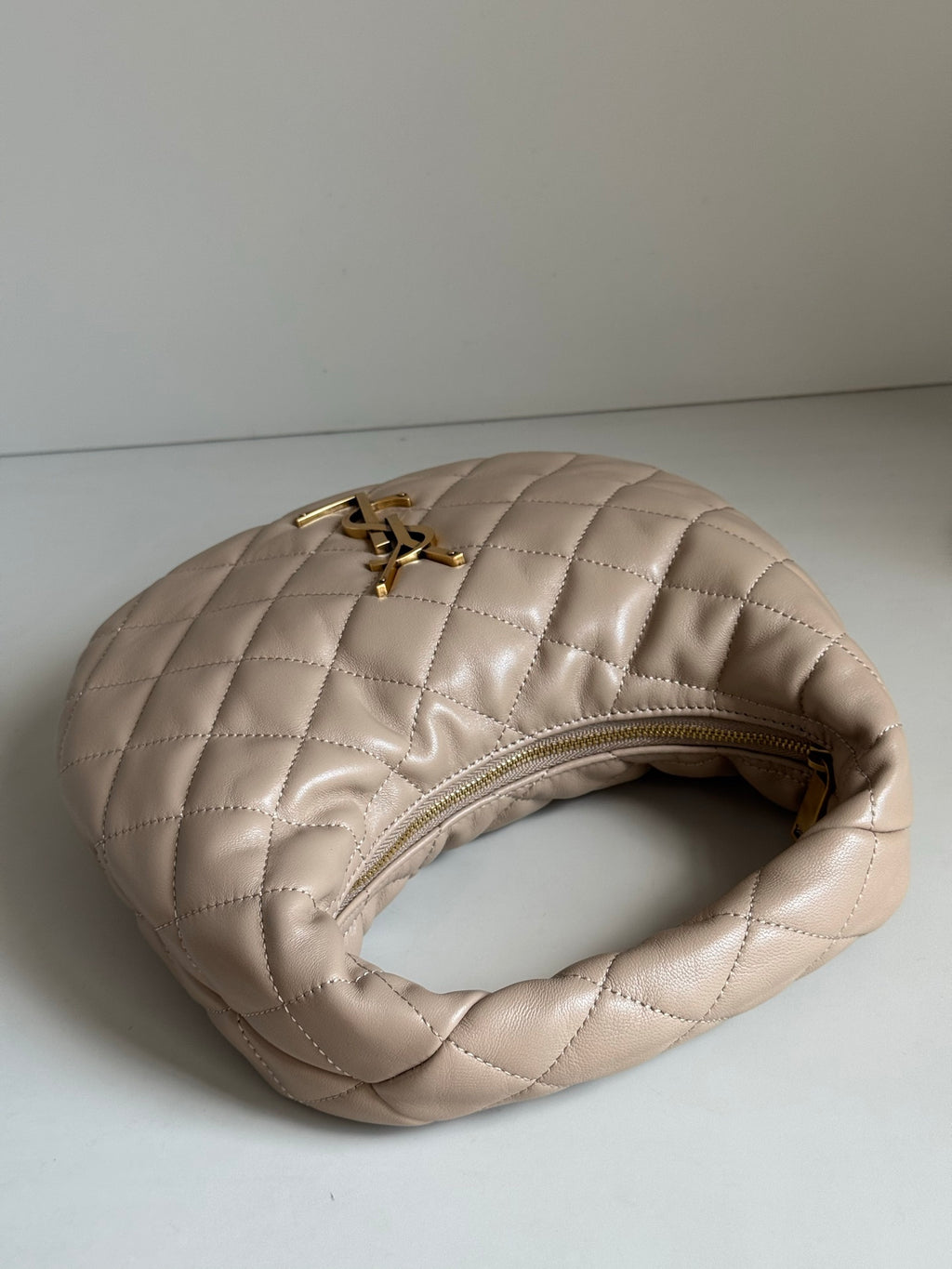 YSL quilted hobo bag side view with gold zipper opening and gold logo charm