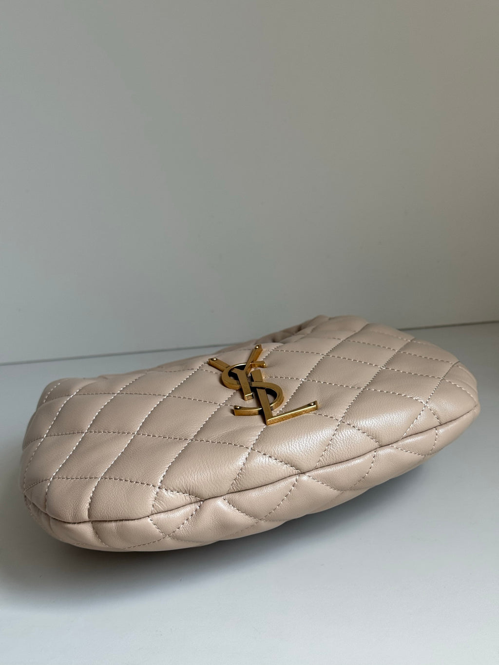 YSL quilted hobo bag side view with gold YSL logo charm and handle hardware