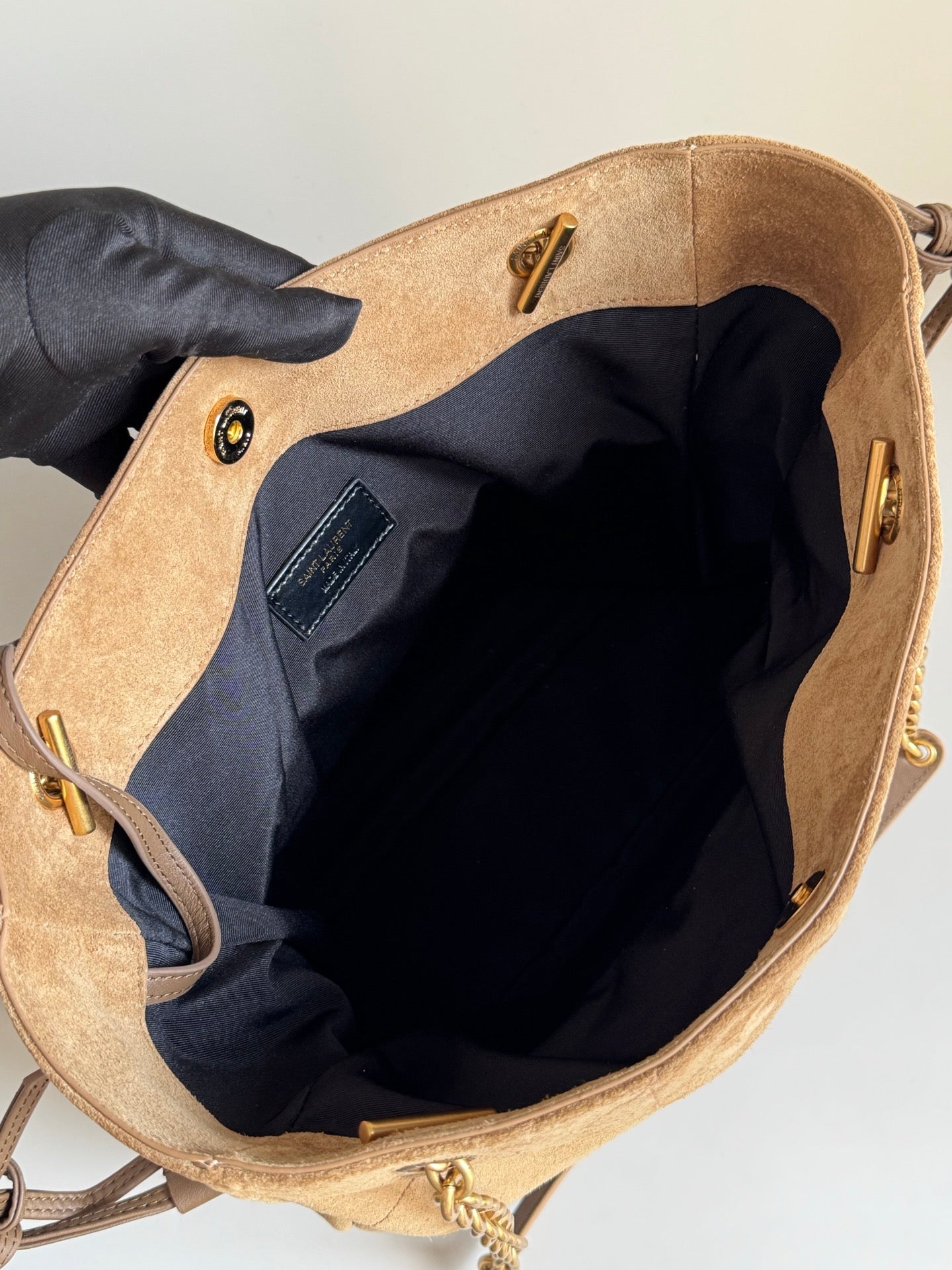 Tan suede bag interior with black lining and zipper pocket, open top view