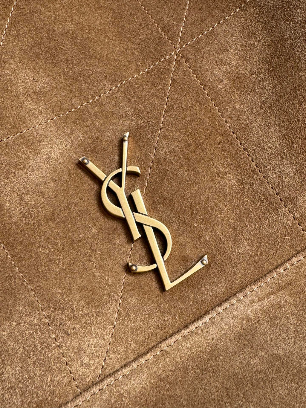 Gold YSL logo emblem on tan quilted suede panel