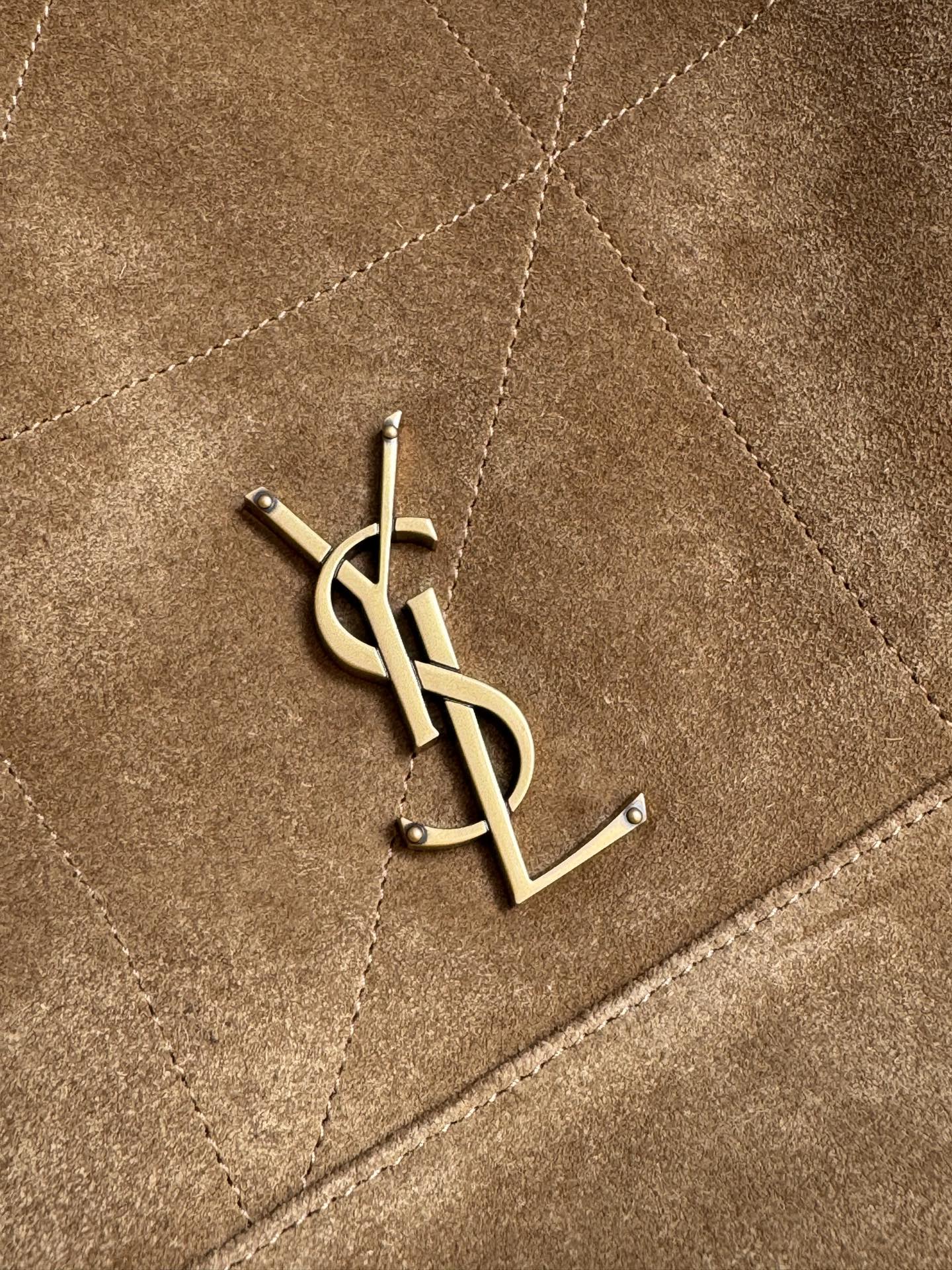 Gold YSL logo emblem on tan quilted suede panel