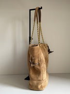 Tan suede tote bag with gold chain handles and side tie details, back view