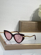 Bvlgari sunglasses with dark red frames, pink lenses, and braided gold temples