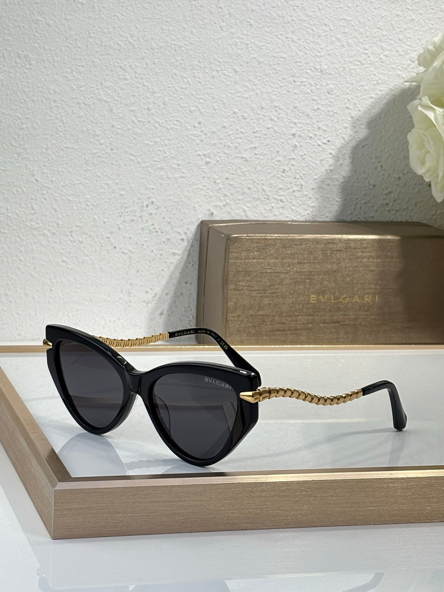 Bvlgari sunglasses with black frames, dark lenses, and gold braided temple cords