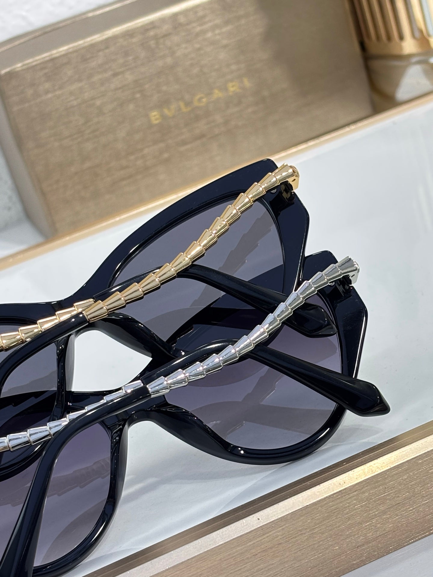 Bvlgari sunglasses close-up showing blue-black frames and metal braided temple detail