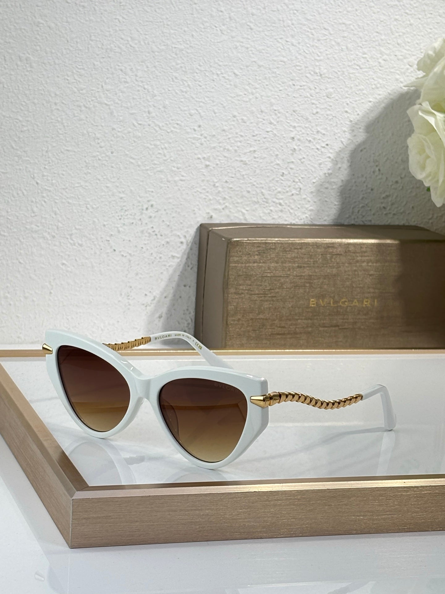 Bvlgari sunglasses with white frames, brown lenses, and braided gold temples