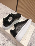 Alexander McQueen lace-up sneakers with black uppers and thick white sole, side view