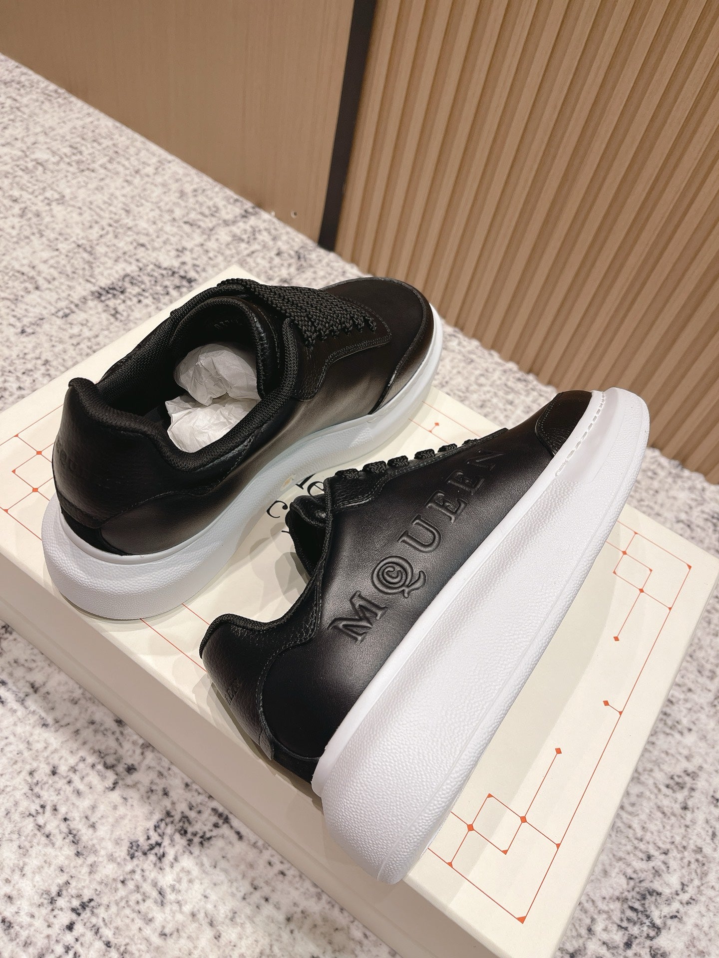 Alexander McQueen lace-up sneakers with black uppers and thick white sole, side view