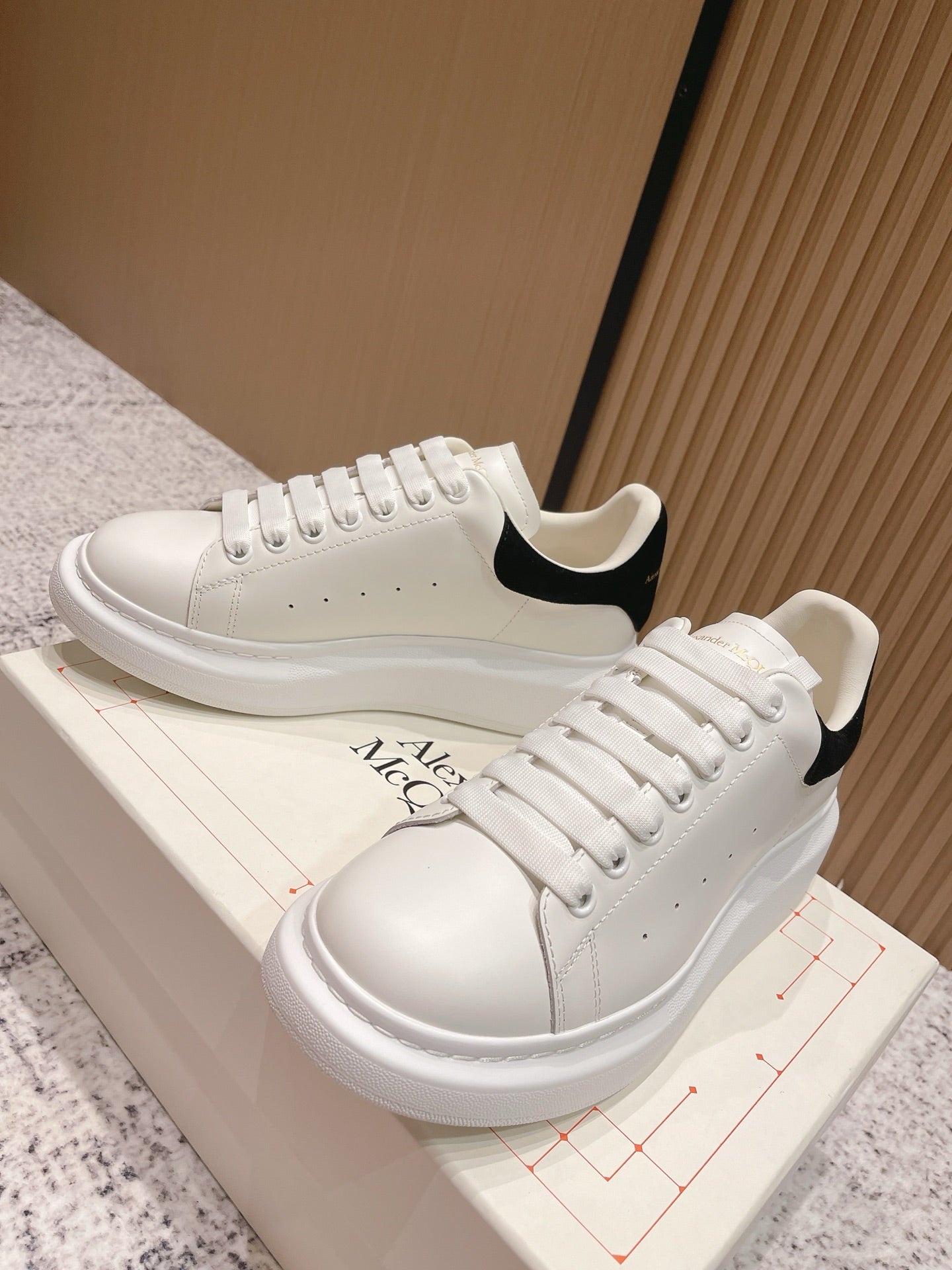 White lace-up sneakers with black heel trim and Alexander McQueen logo on side