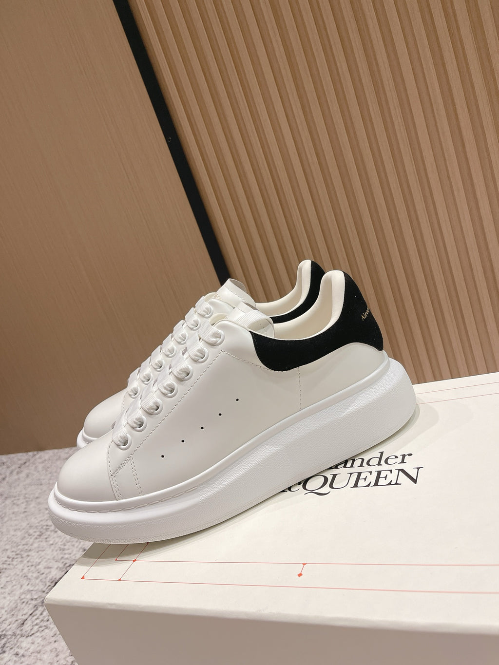 White lace-up sneakers with black collar trim and chunky white sole