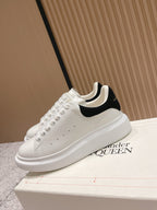 White lace-up sneakers with black collar trim and chunky white sole