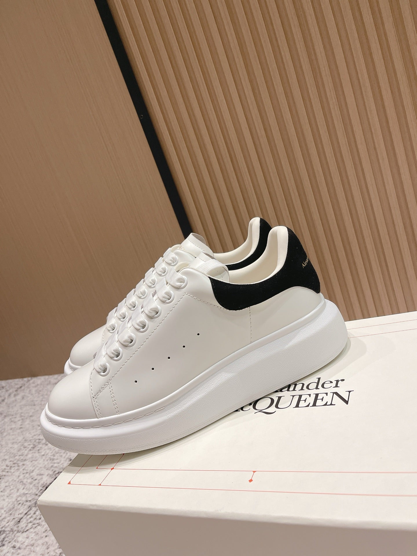 White lace-up sneakers with black collar trim and chunky white sole