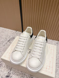 Pair of white lace-up sneakers with black heel accents on a shoebox