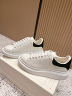 White leather lace-up sneakers with black heel trim and perforated toe holes