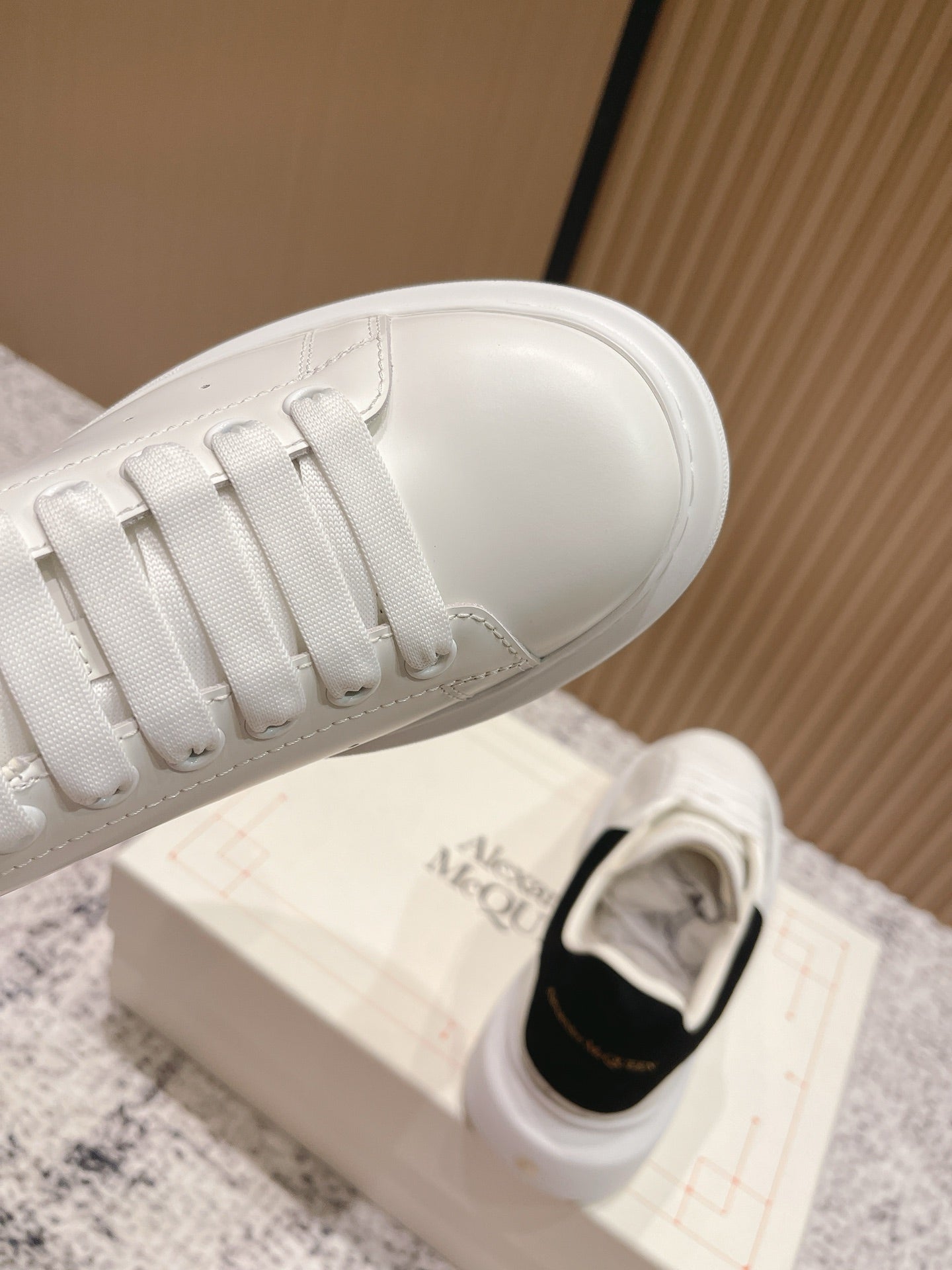 White sneaker lace front with black heel lining visible near opening