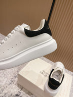 White sneaker profile with black heel tab and thick rubber sole, side view