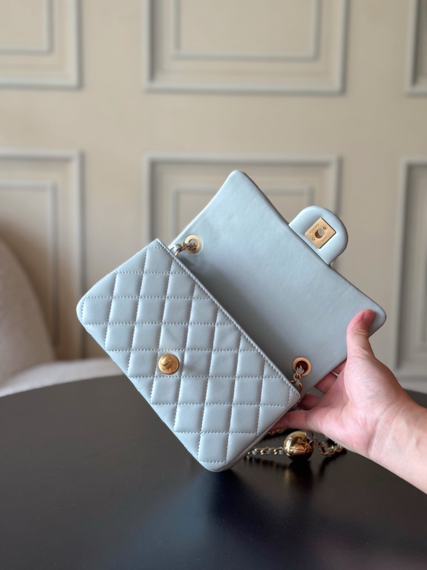 Chanel quilted flap bag in light blue held in hand, gold turn-lock detail