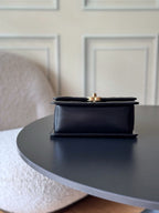 Black flap shoulder bag with hinged top and gold-tone hardware