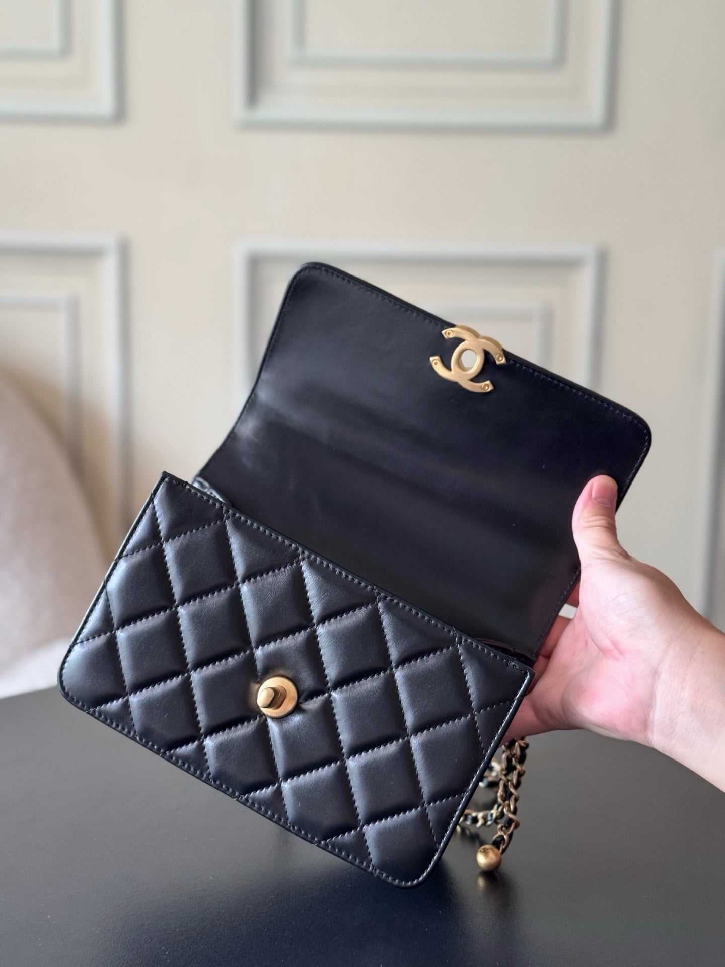 Black quilted crossbody flap bag held in hand with gold CC emblem