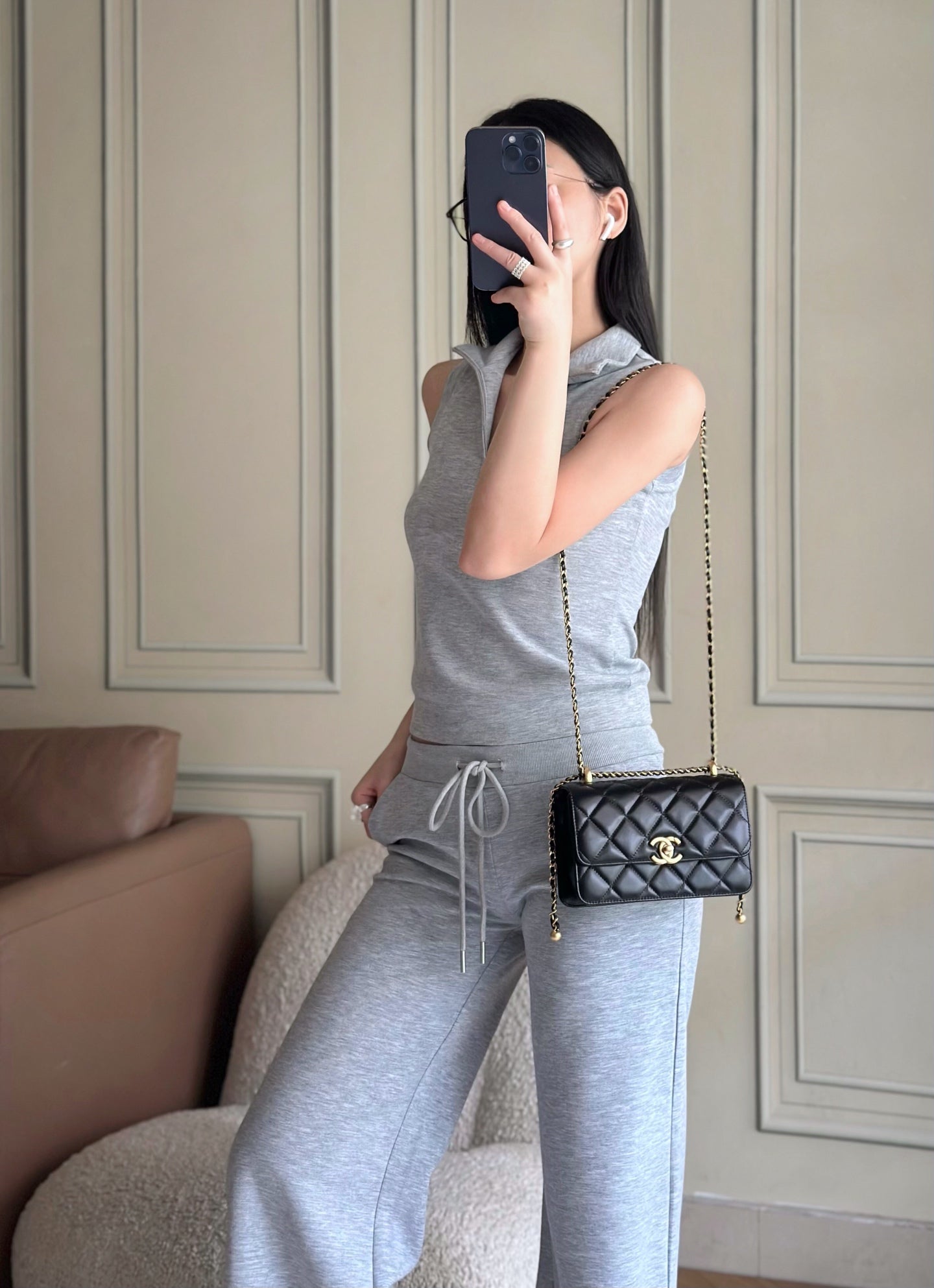 Model holding quilted black shoulder bag with gold chain and CC logo