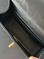 Interior view of black shoulder bag with double compartment and gold zipper pull