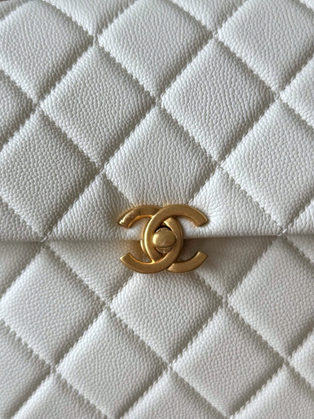 Chanel quilted bag front detail in white with gold CC logo clasp