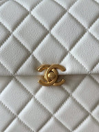 Chanel quilted bag front detail in white with gold CC logo clasp