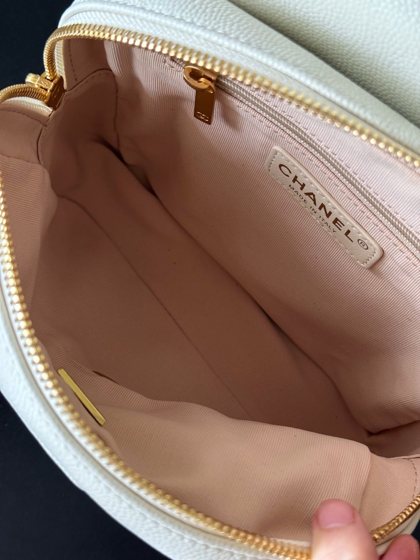 Chanel bag interior with beige lining and gold zipper trim, marked “CHANEL”