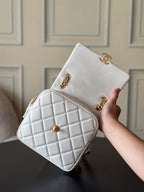 Chanel quilted mini bag in white with gold chain strap held in a hand