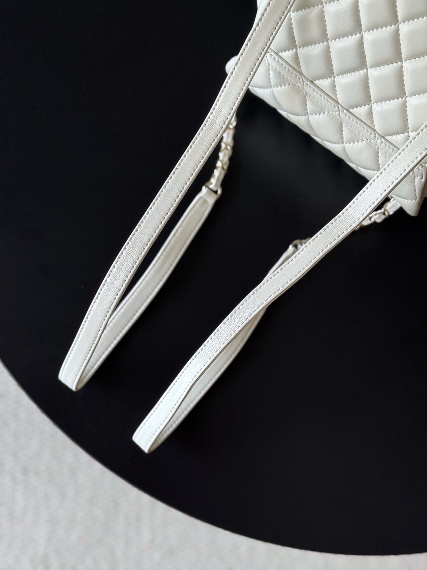 Chanel white quilted bag with chain shoulder straps and slim leather handle.