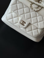 Chanel quilted white flap bag corner with CC emblem and stitched leather trim.