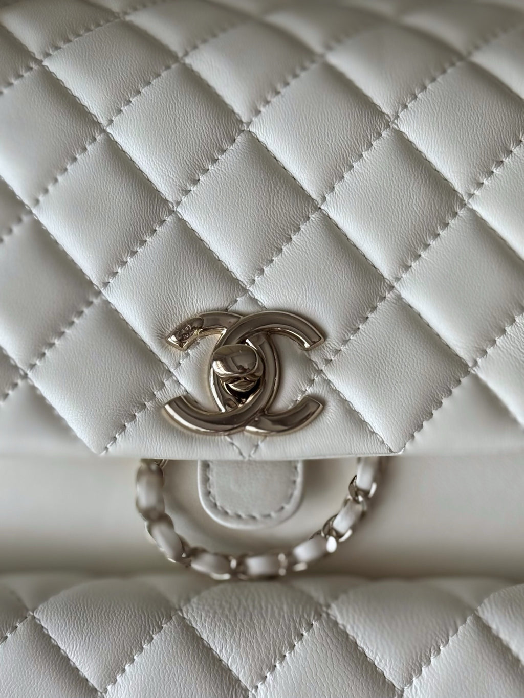 Chanel quilted white flap bag with embossed CC logo and chain strap rings.