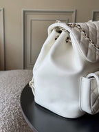 Chanel white quilted bucket bag with chain strap and metal hardware detail.