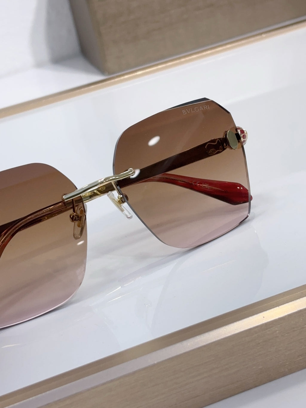 Bvlgari sunglasses with brown gradient lenses and red-toned temple arms