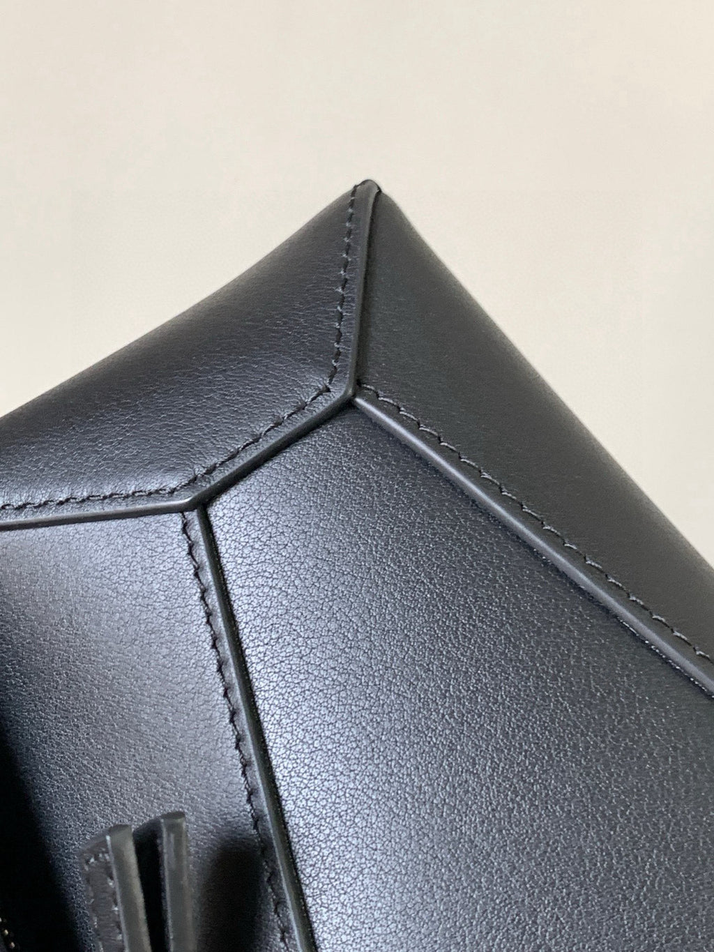 Dark leather bag corner panel with stitched seams and pointed edge detail