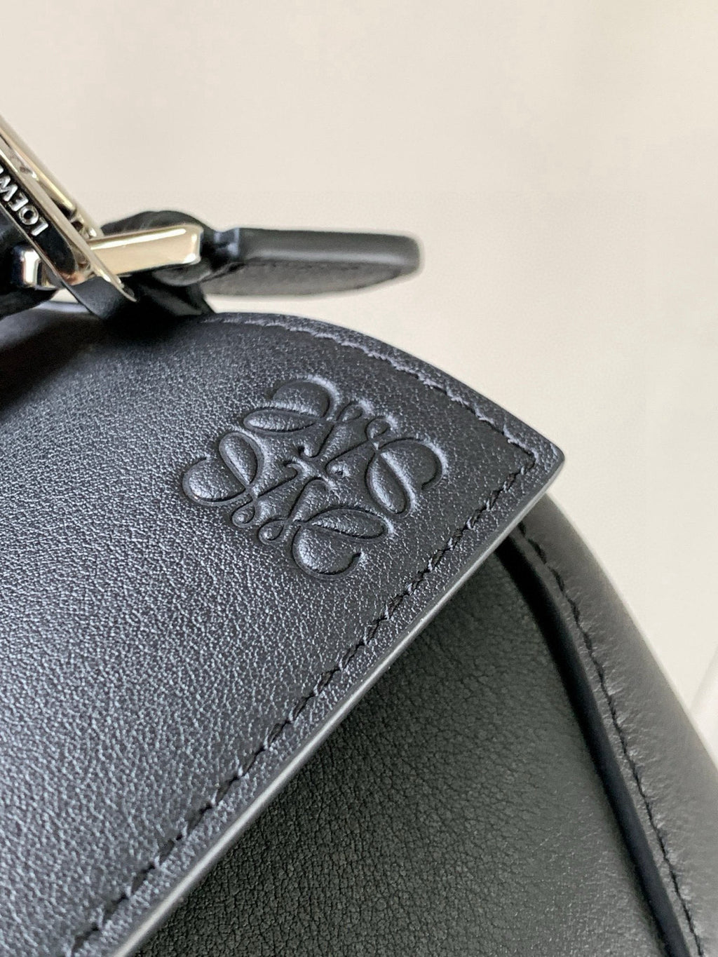Loewe navy leather bag detail with embossed logo patch and stitched edge
