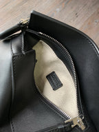 Dark leather bag interior with beige lining, zipper track, and Loewe fabric label