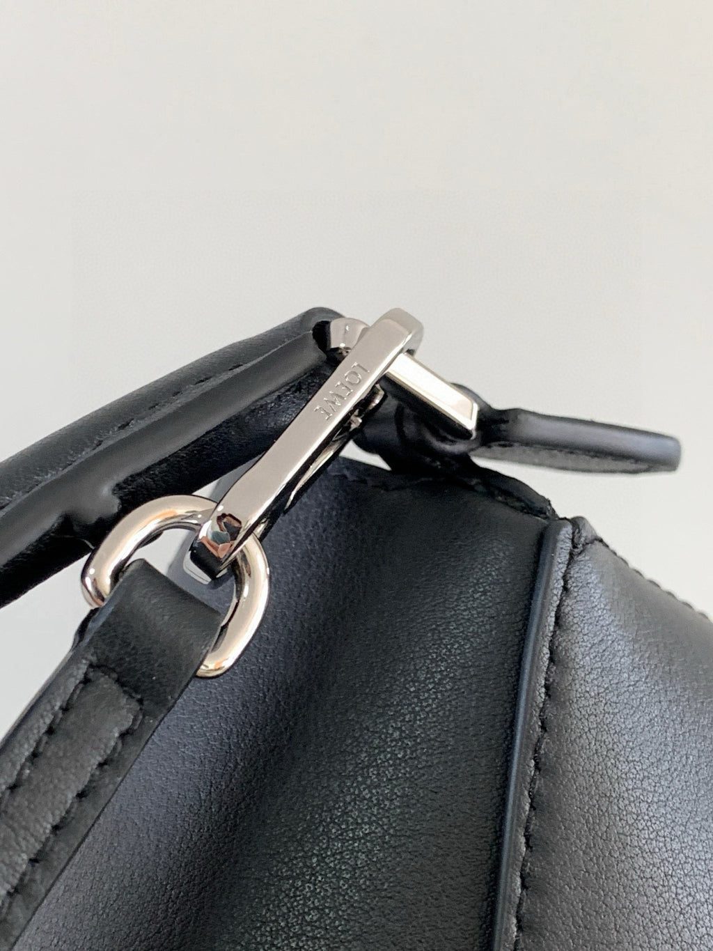Silver clasp and ring on dark leather bag with side strap attachment