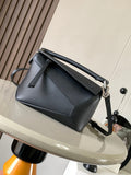 Small dark leather crossbody bag with top handle, adjustable strap, and silver clasp