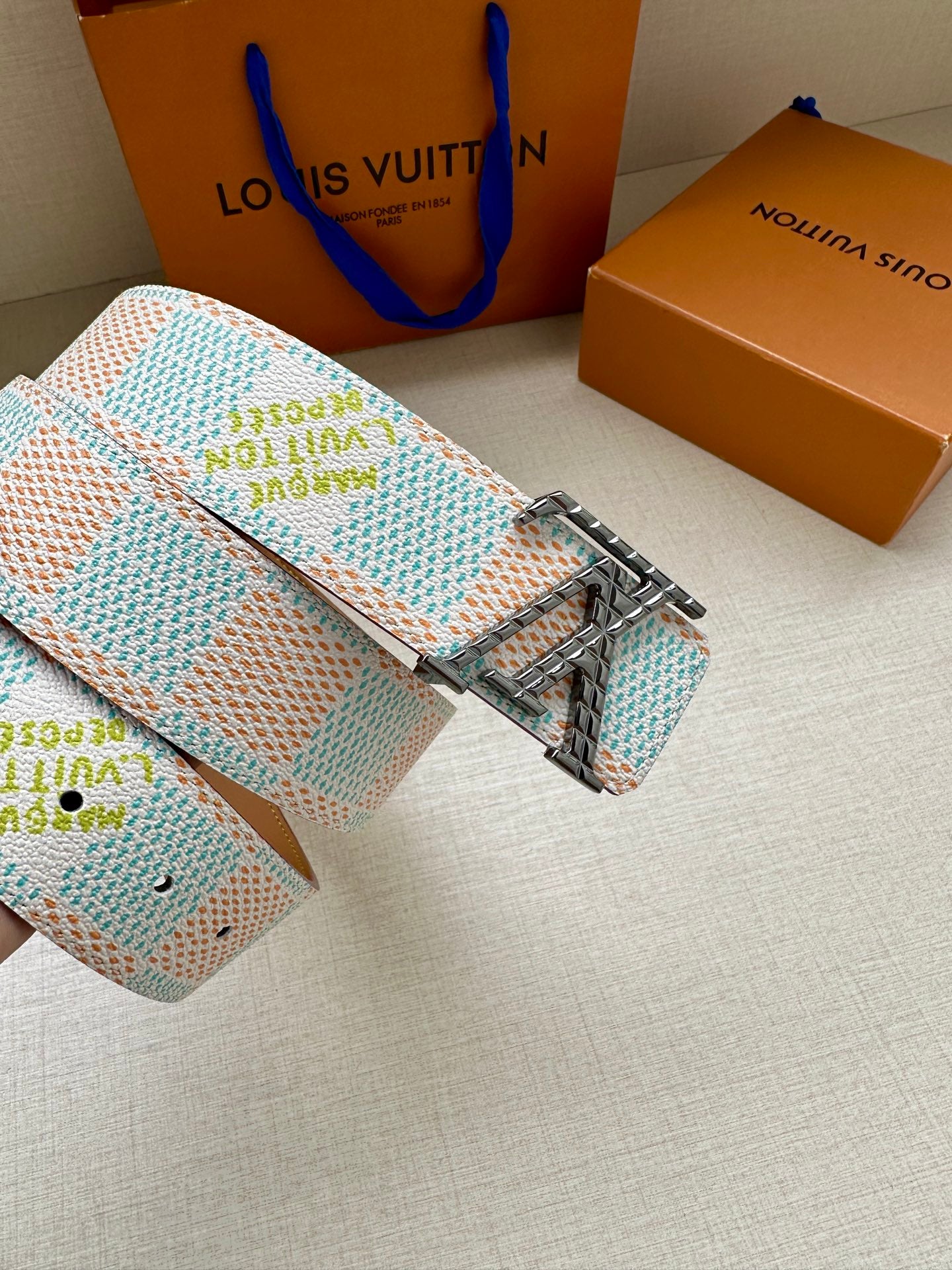 Louis Vuitton belt coiled with turquoise-and-white patterned strap and gold buckle