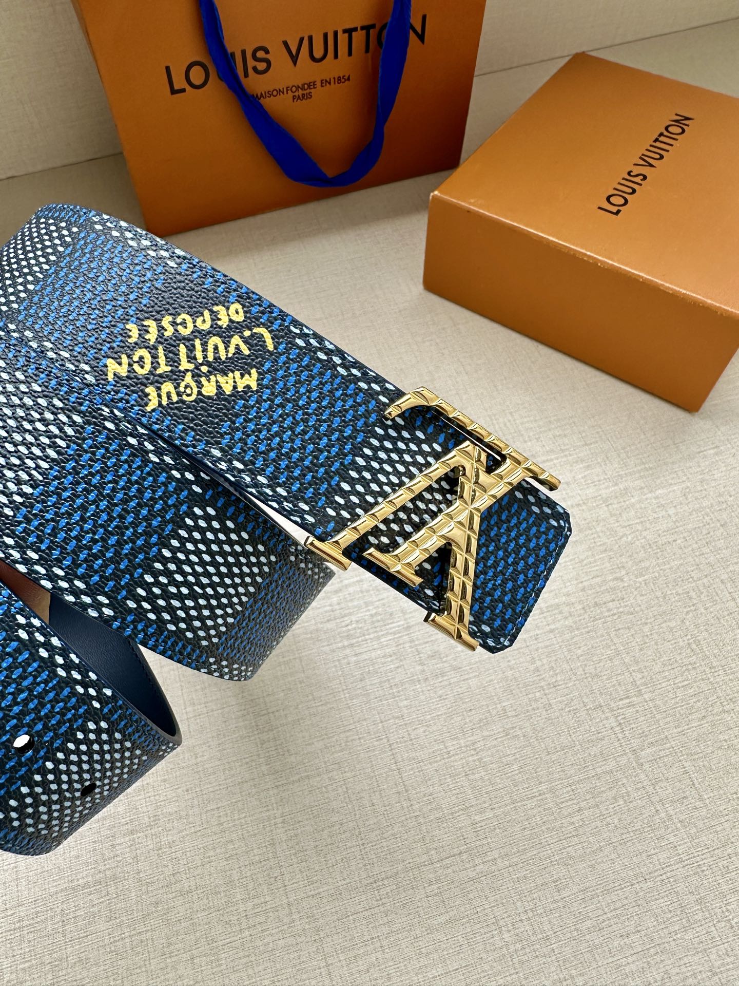 Blue patterned Louis Vuitton belt buckle detail with engraved silver hardware