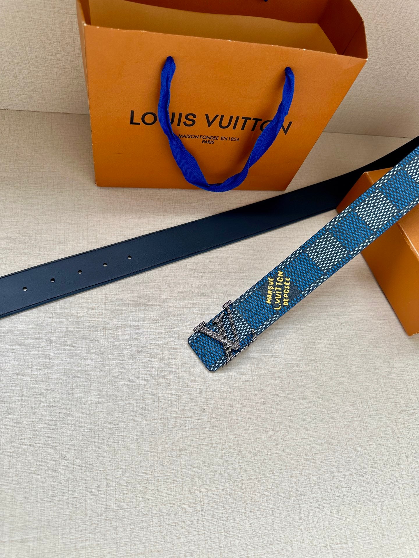 Blue Louis Vuitton belt strap with perforations and printed logo text