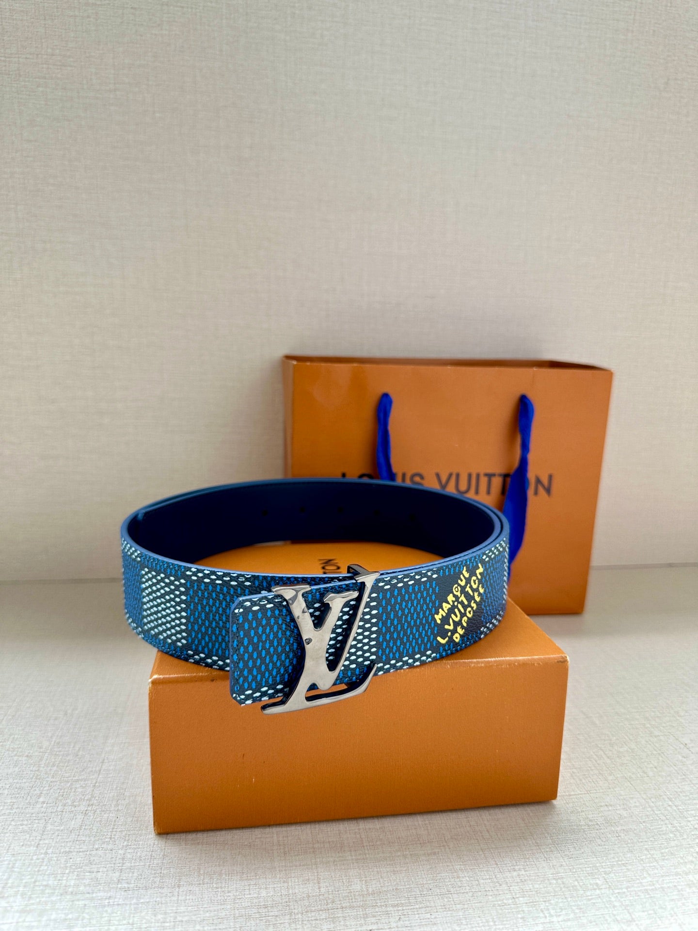 Louis Vuitton belt stacked on box: blue check strap with gold LV buckle