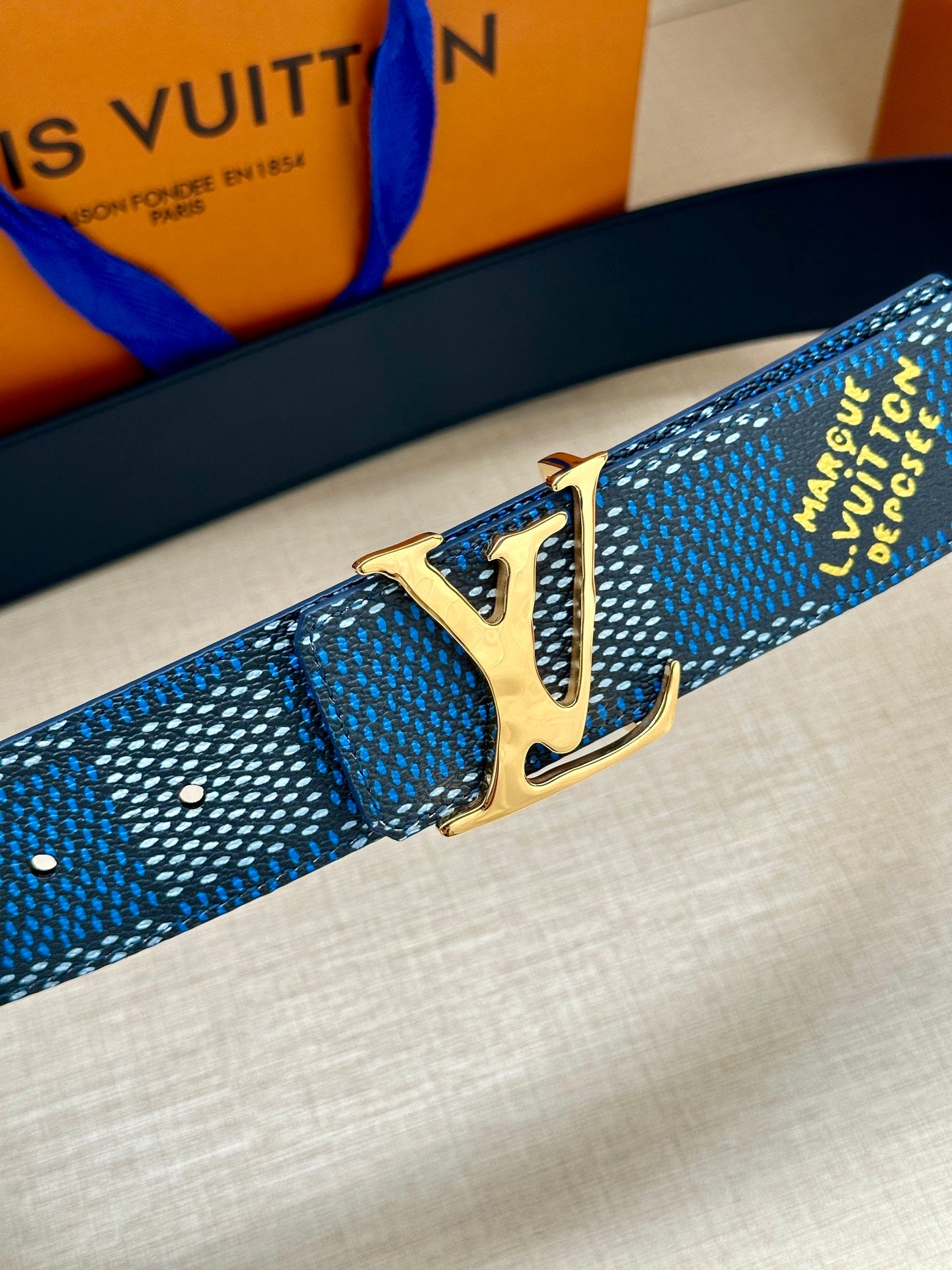 Louis Vuitton belt detail: blue check strap with gold LV buckle and stitching