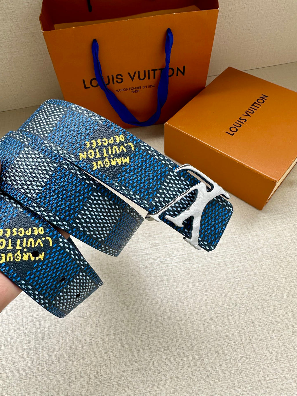 Louis Vuitton belt close-up: blue check strap, gold LV buckle, stamped text